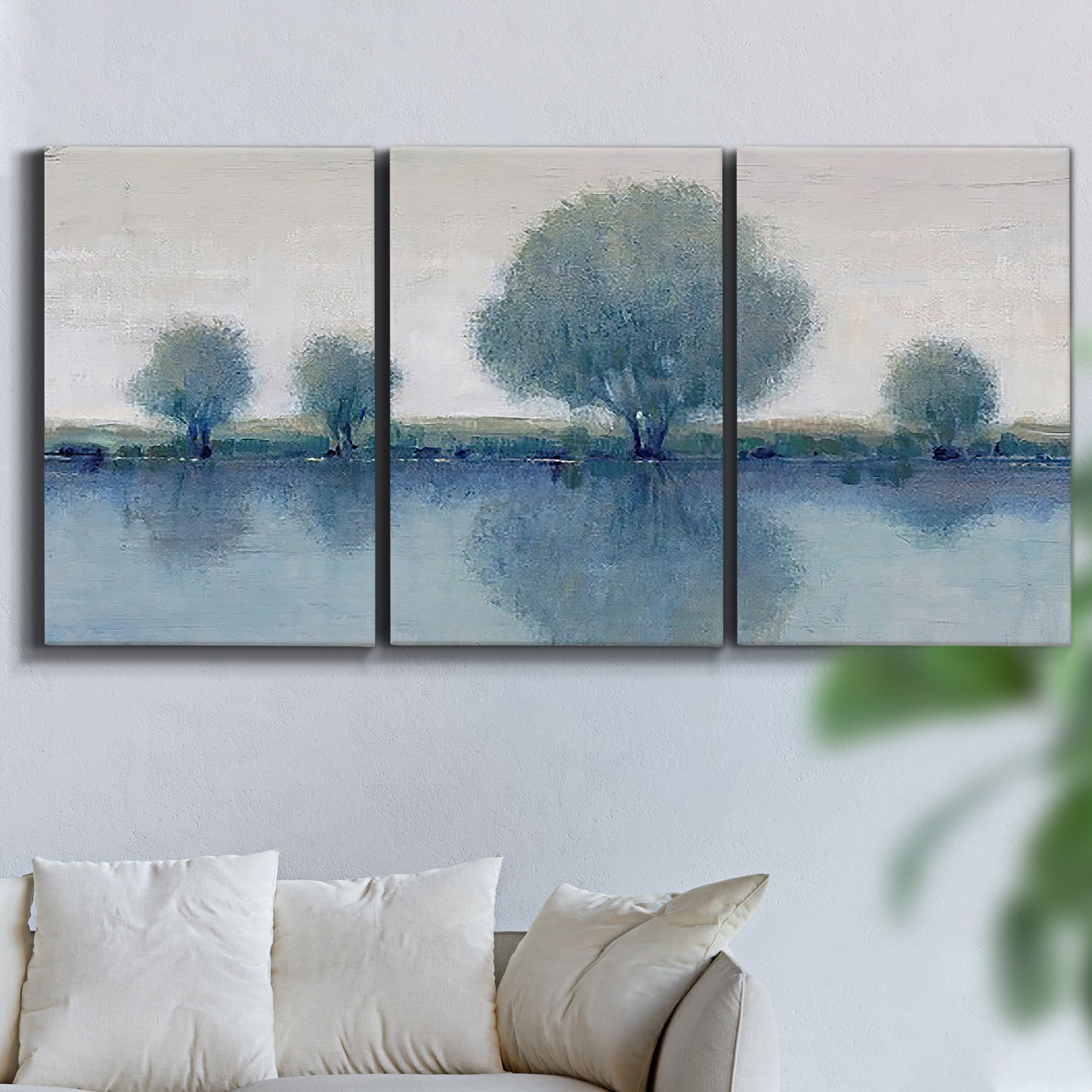 Three-panel canvas wall art featuring calm afternoon river reflection, displayed in a living room above a sofa.