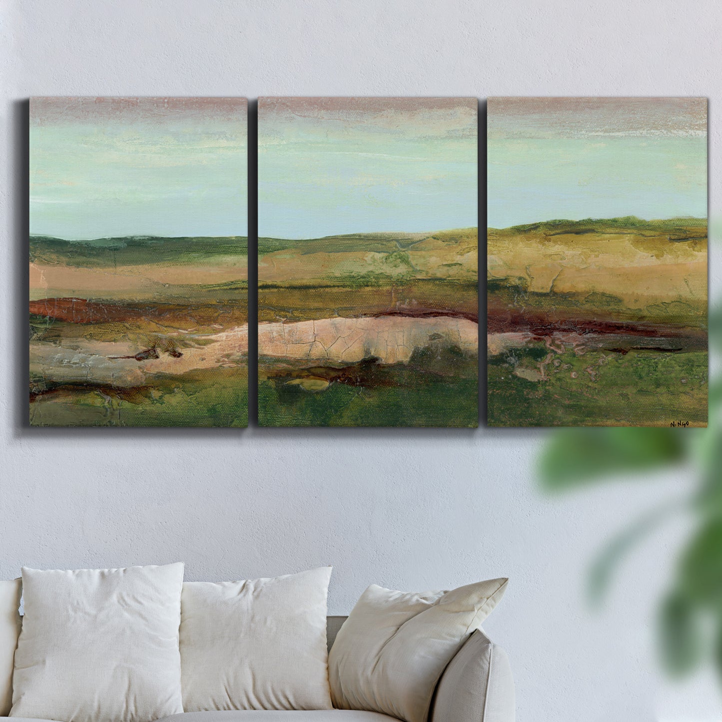 Three-panel canvas wall art featuring pastoral landscape with winding road, displayed in a living room above a sofa.