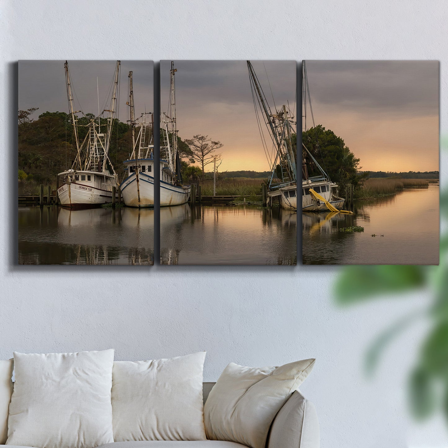 Three-panel canvas wall art featuring fishing trawlers on working harbor, displayed in a living room above a sofa.