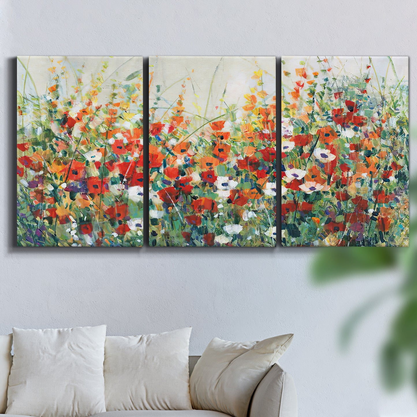 Three-panel canvas wall art featuring colorful garden flowers in bloom, displayed in a living room above a sofa.