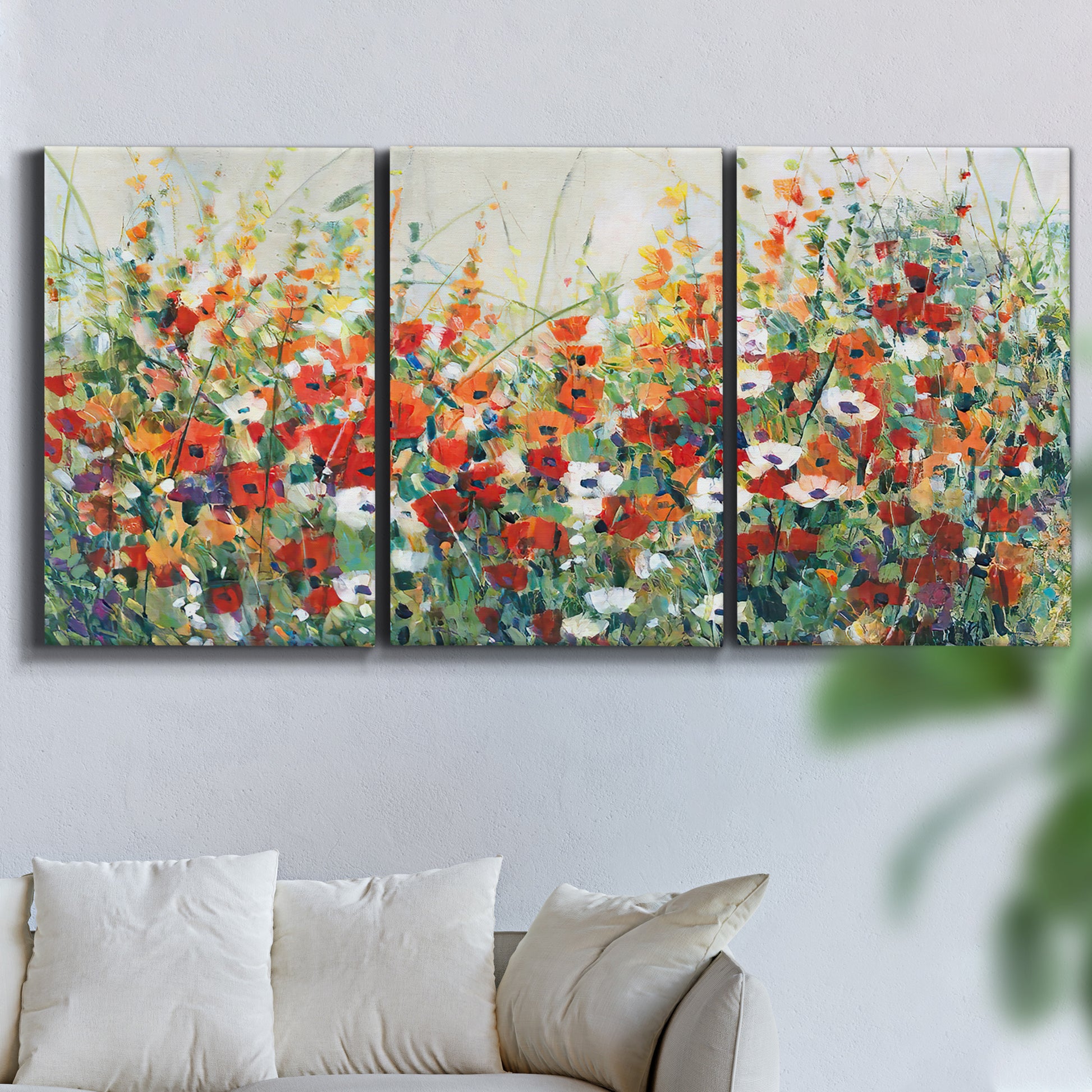 Three-panel canvas wall art featuring colorful garden flowers in bloom, displayed in a living room above a sofa.