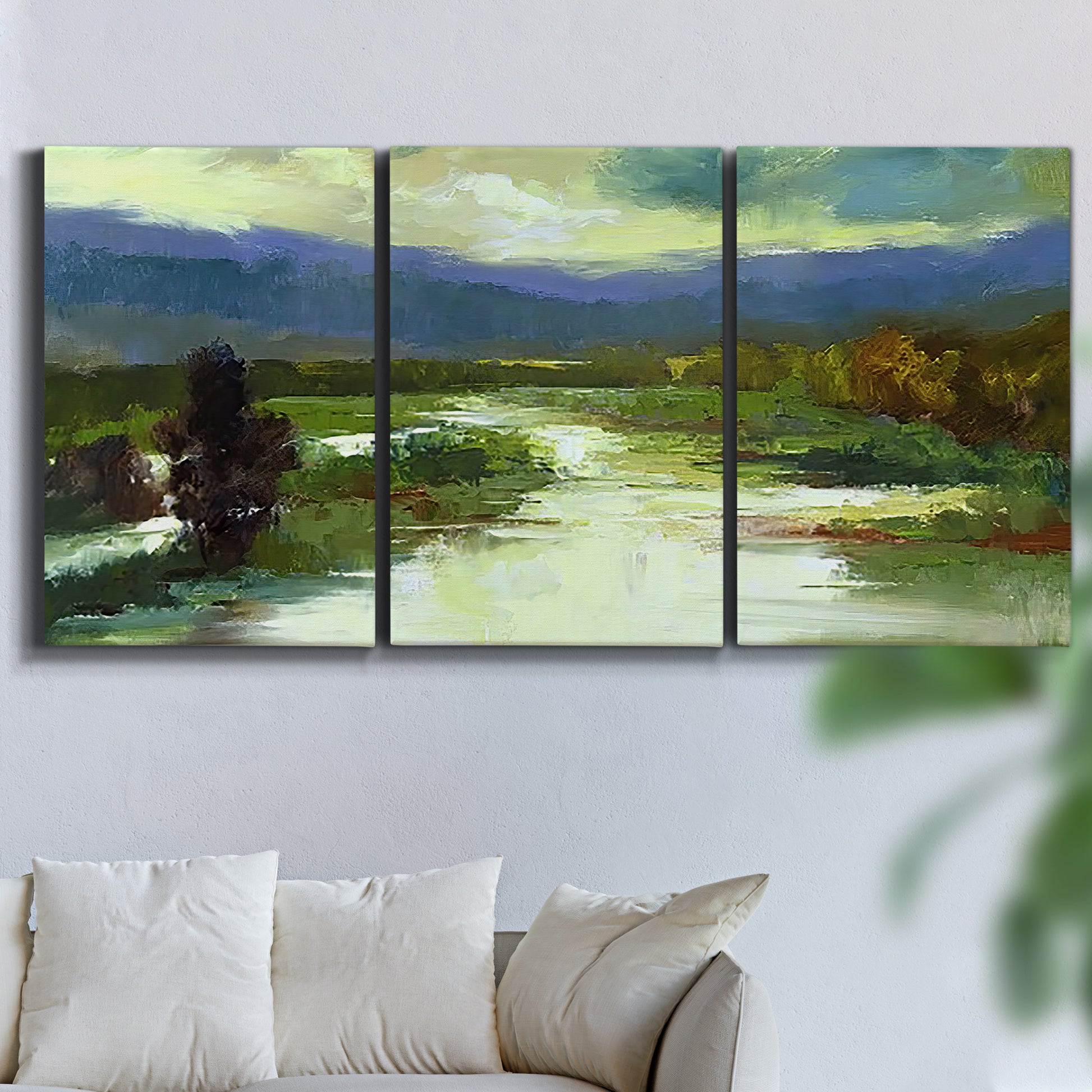 Three-panel canvas wall art featuring open meadow landscape with distant hills, displayed in a living room above a sofa.
