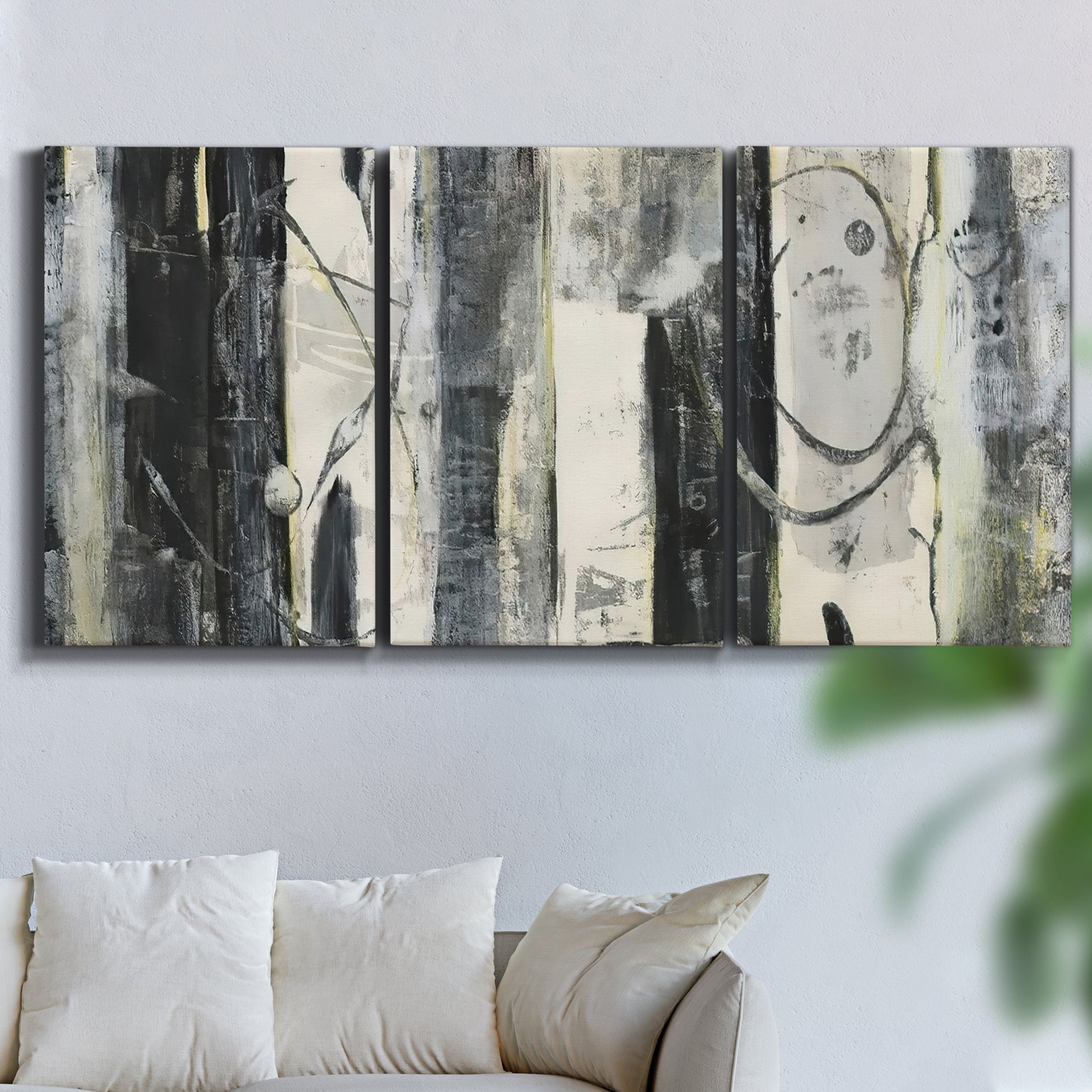 Three-panel canvas wall art featuring vertical abstract tree forms, displayed in a living room above a sofa.