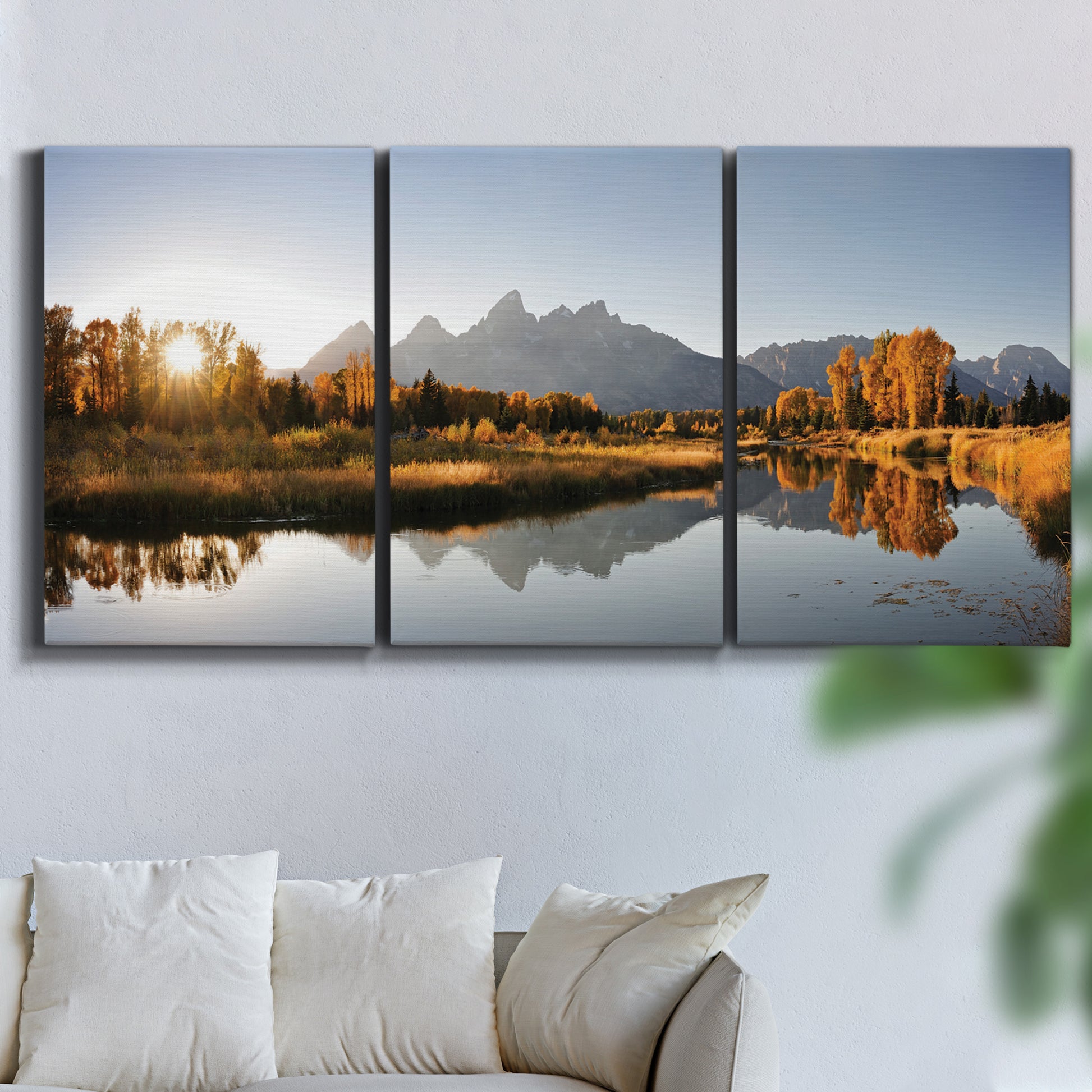 Three-panel canvas wall art featuring river canyon landscape photograph, displayed in a living room above a sofa.