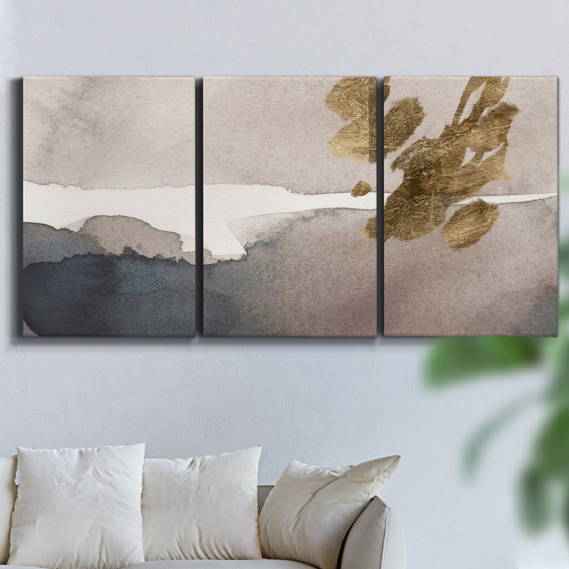 Three-panel canvas wall art featuring abstract watercolor with gold accents, displayed in a living room above a sofa.