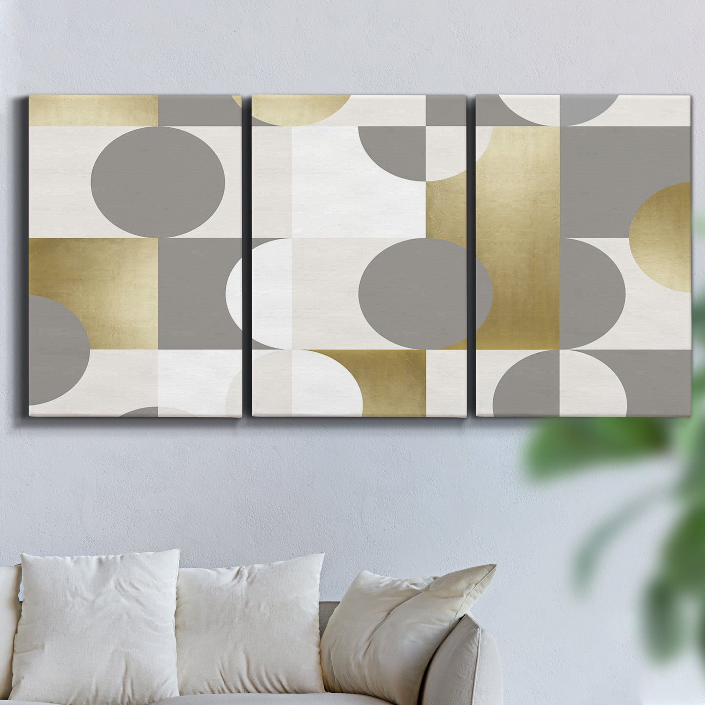 Three-panel canvas wall art featuring geometric gold abstract reflections, displayed in a living room above a sofa.