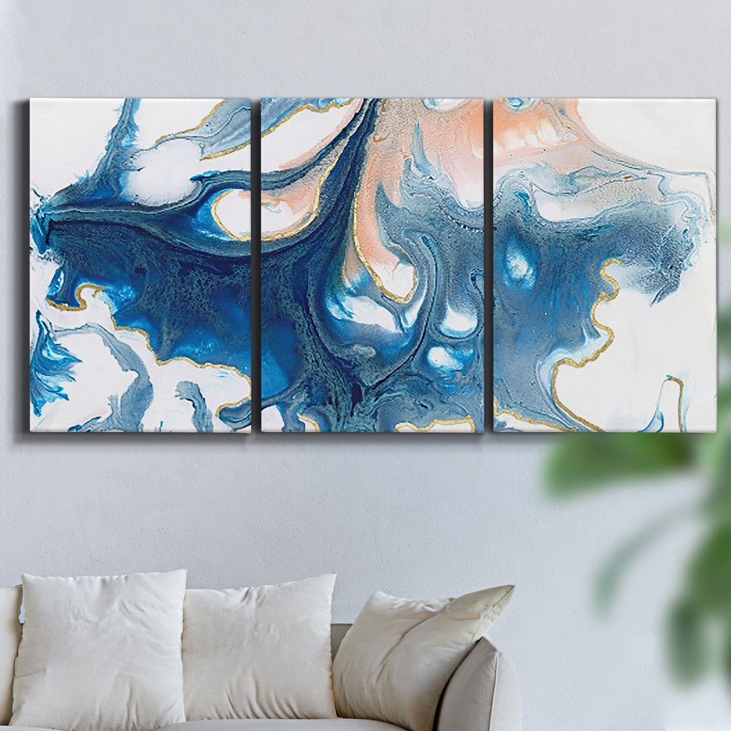 Three-panel canvas wall art featuring flowing blue abstract movement, displayed in a living room above a sofa.
