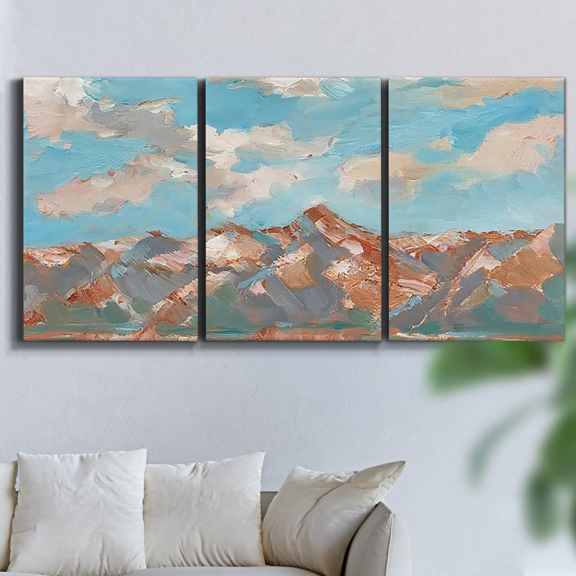 Three-panel canvas wall art featuring soft pastel western hills landscape, displayed in a living room above a sofa.