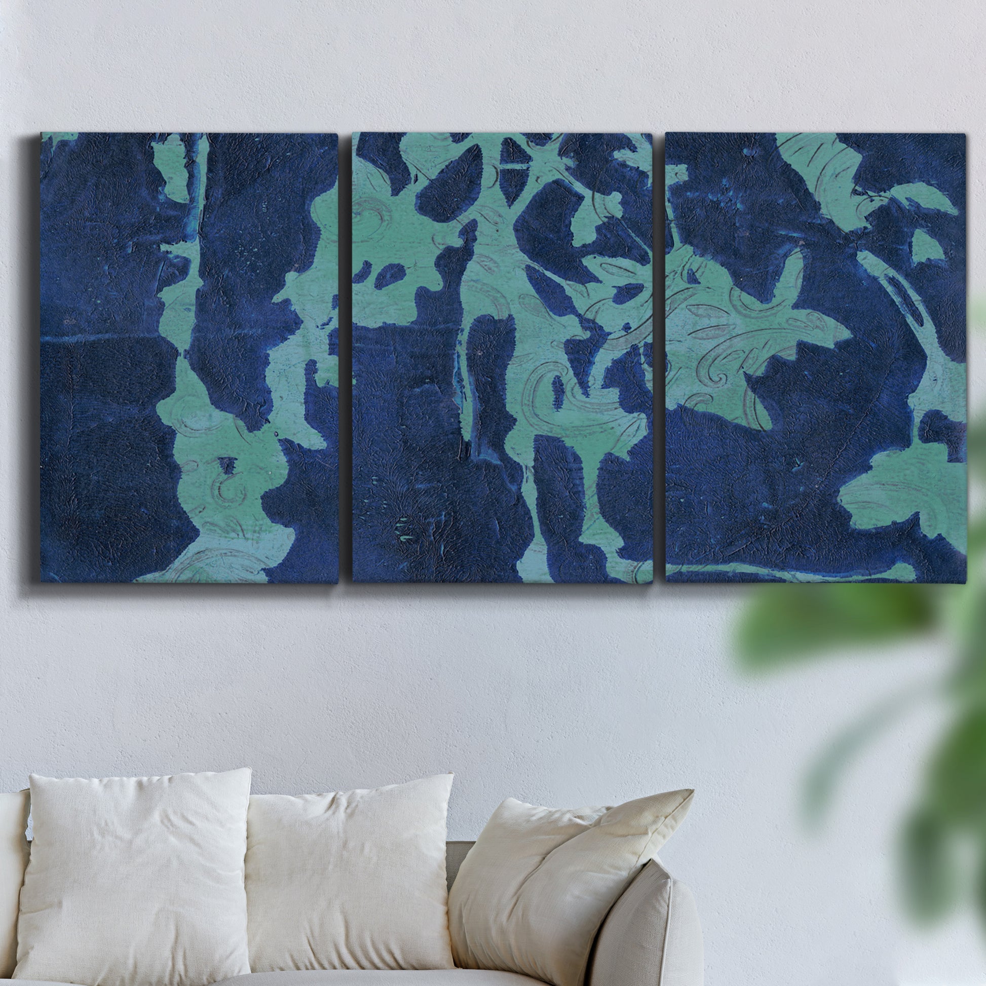 Three-panel canvas wall art featuring abstract floral shapes, displayed in a living room above a sofa.