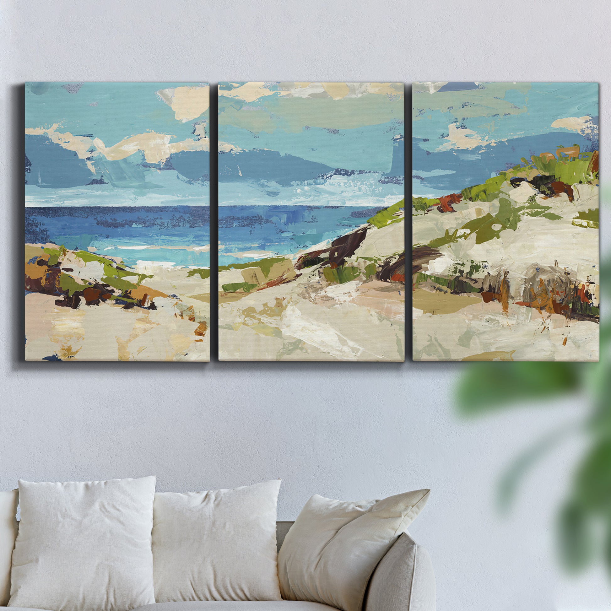 Three-panel canvas wall art featuring sand dunes beside open water, displayed in a living room above a sofa.
