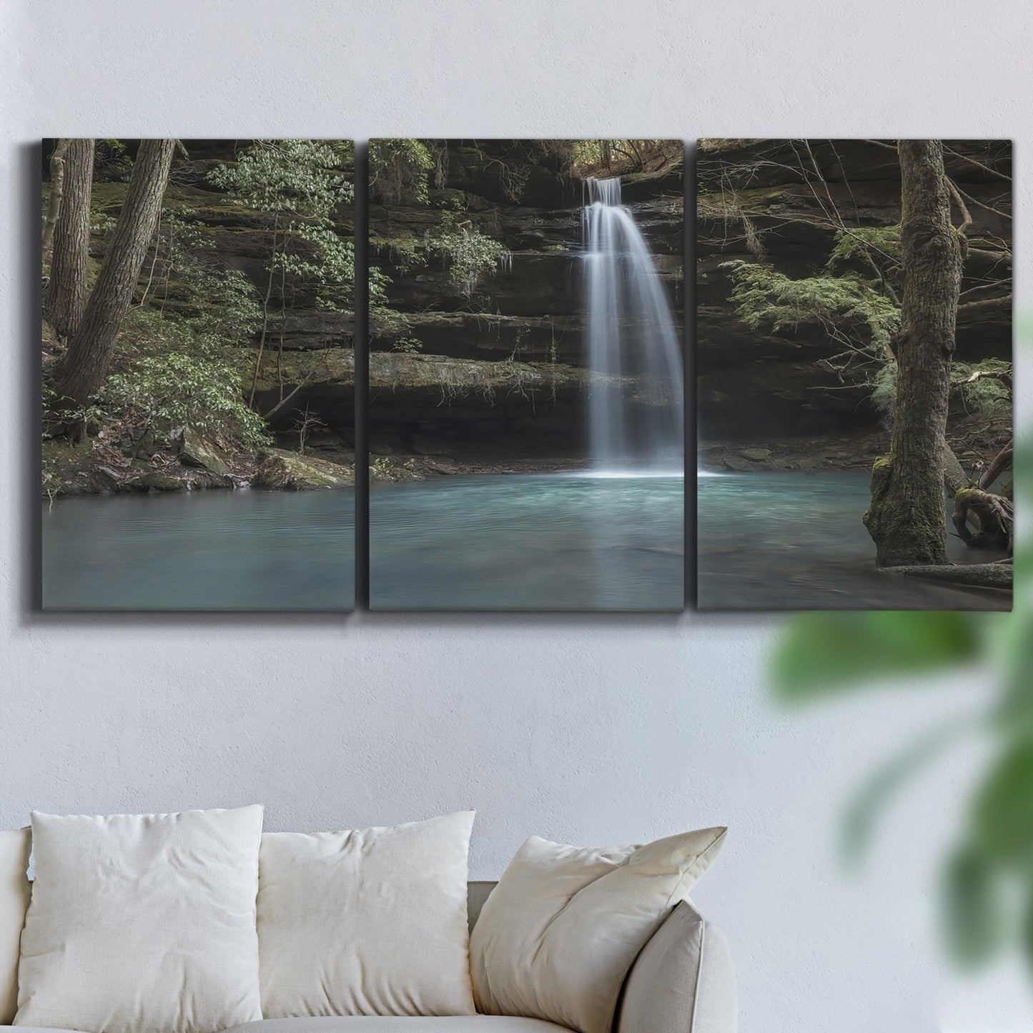 Three-panel canvas wall art featuring waterfall cascading through forest, displayed in a living room above a sofa.