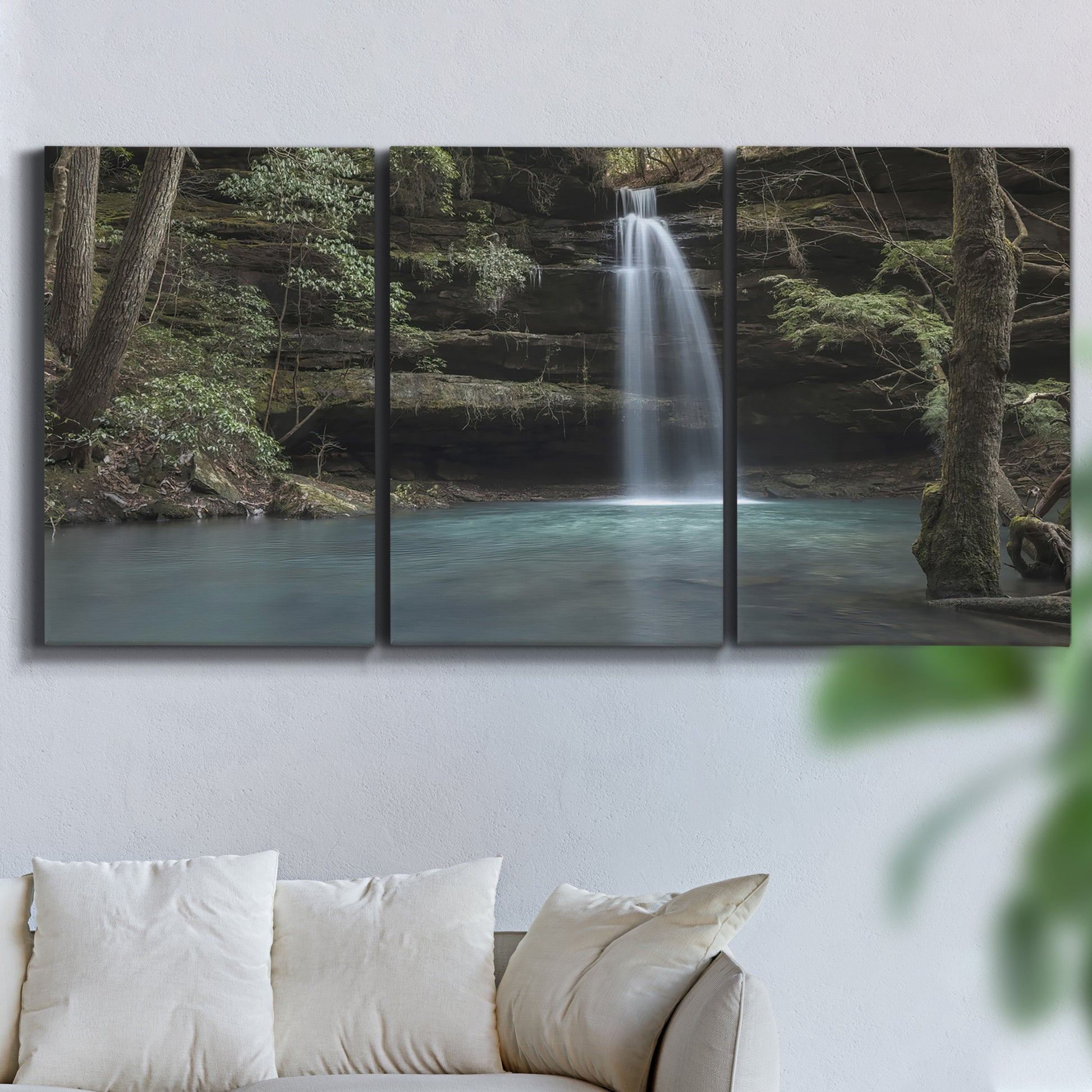 Three-panel canvas wall art featuring waterfall cascading through forest, displayed in a living room above a sofa.