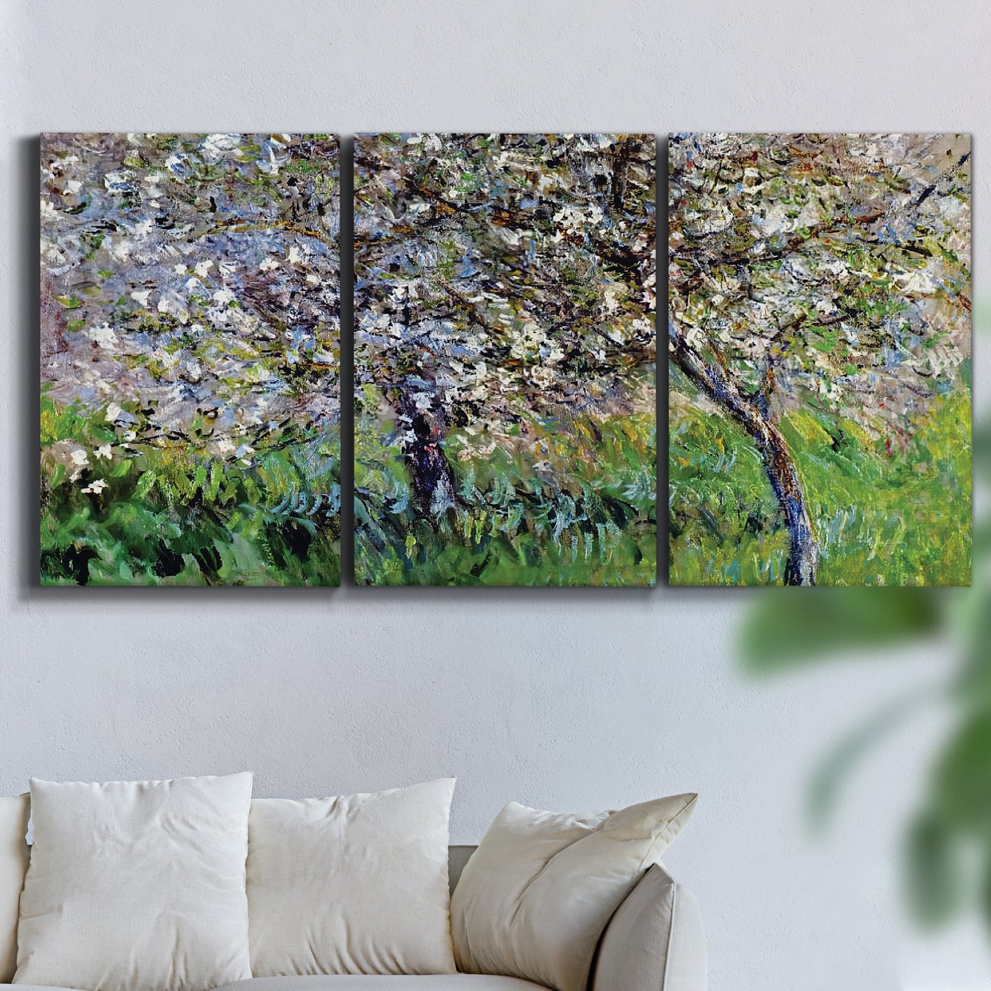 Three-panel canvas wall art featuring apple trees blooming beside water, displayed in a living room above a sofa.