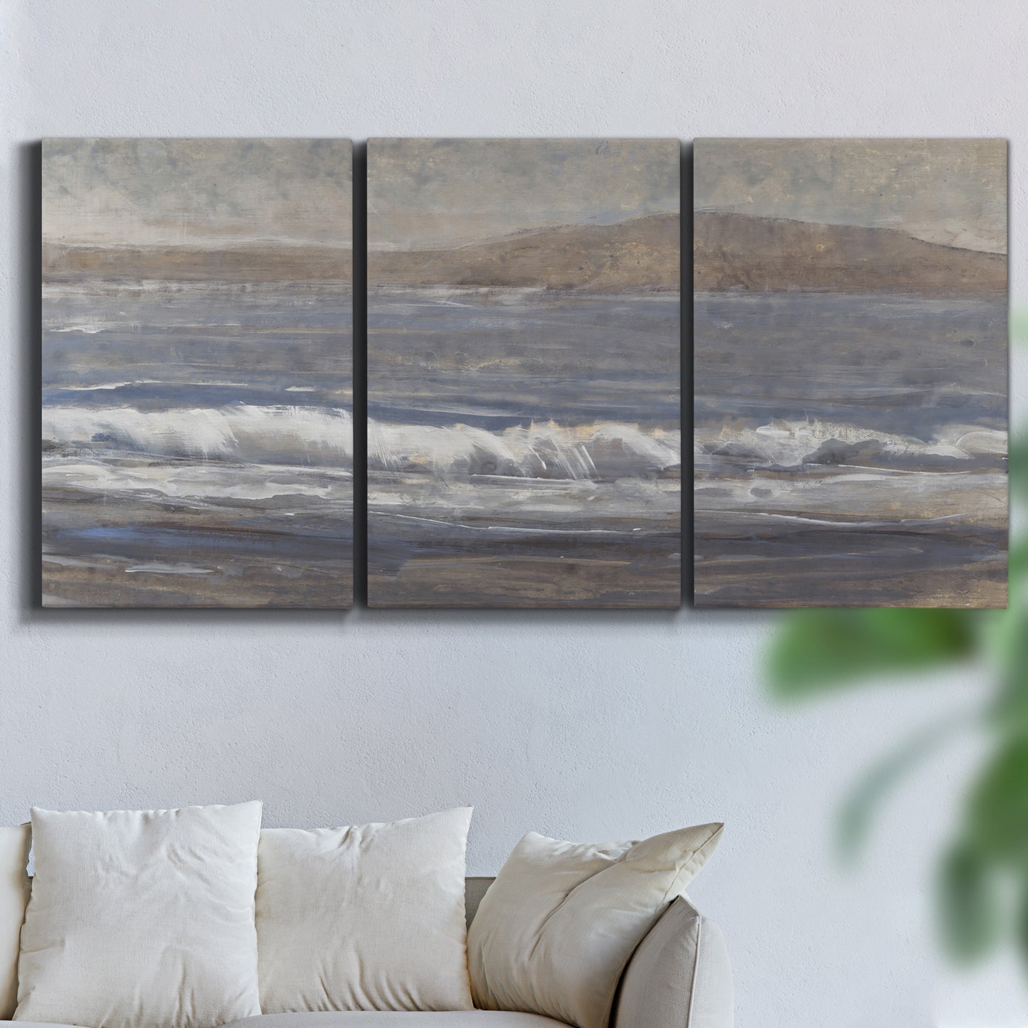 Three-panel canvas wall art featuring shoreline between land and sea, displayed in a living room above a sofa.