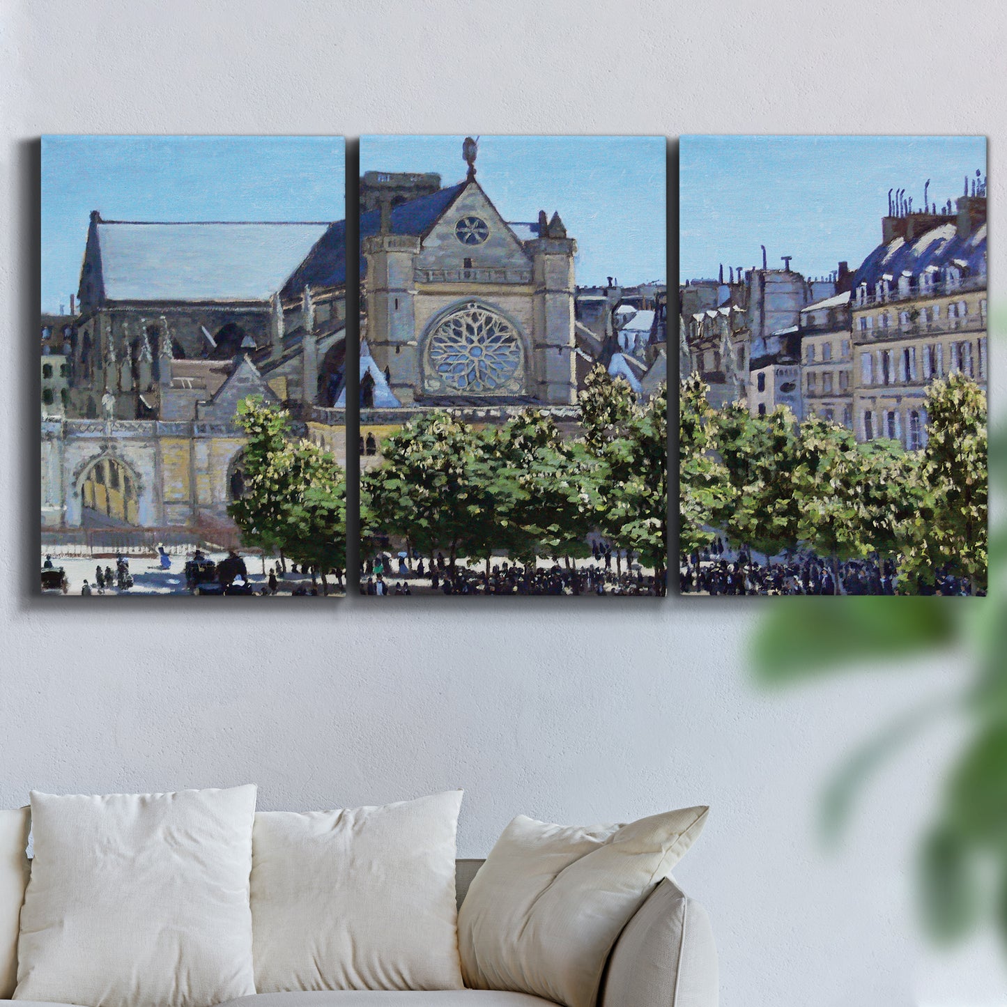 Three-panel canvas wall art featuring gothic church within city setting, displayed in a living room above a sofa.
