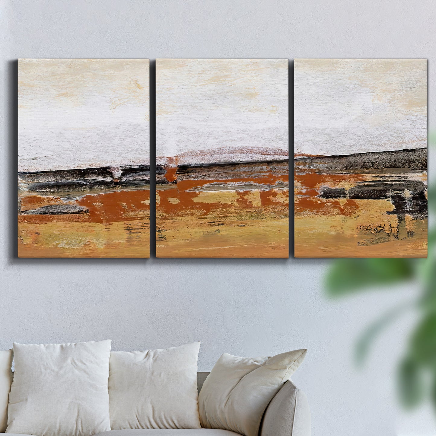 Three-panel canvas wall art featuring abstract bridge landscape in ochre, displayed in a living room above a sofa.