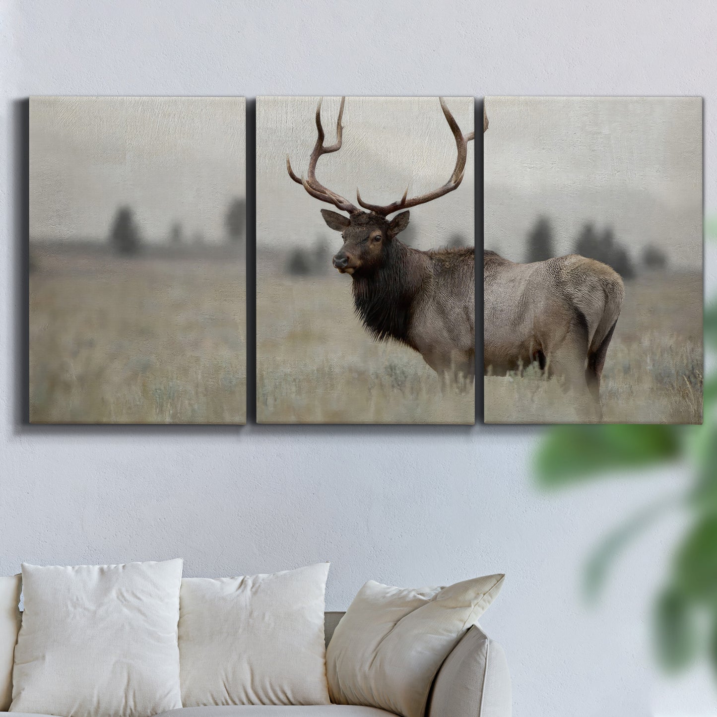 Three-panel canvas wall art featuring elk standing in open grassland, displayed in a living room above a sofa.