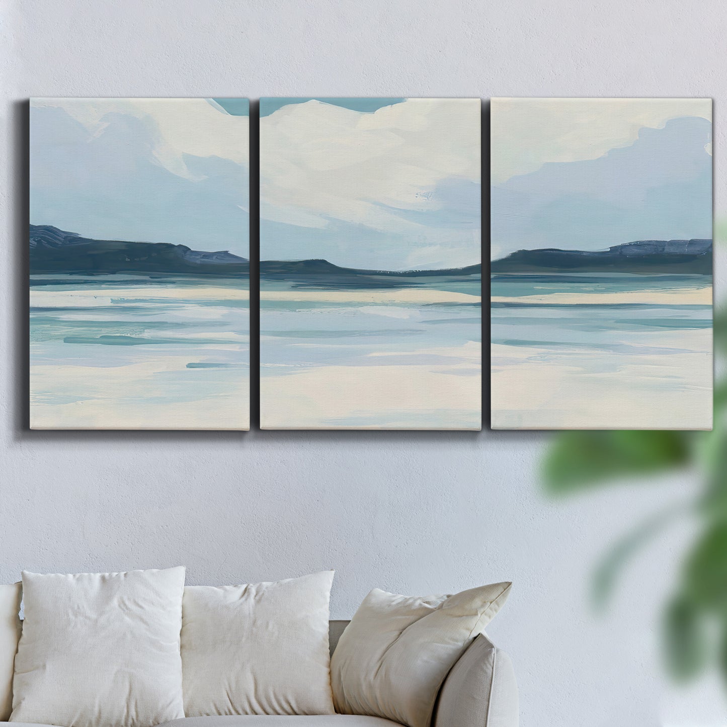 Three-panel canvas wall art featuring soft coastal shoreline landscape, displayed in a living room above a sofa.