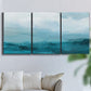 Three-panel canvas wall art featuring vertical coastal elements with rising light, displayed in a living room above a sofa.