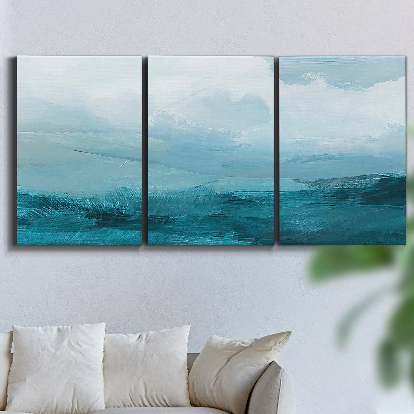 Three-panel canvas wall art featuring vertical coastal elements with rising light, displayed in a living room above a sofa.