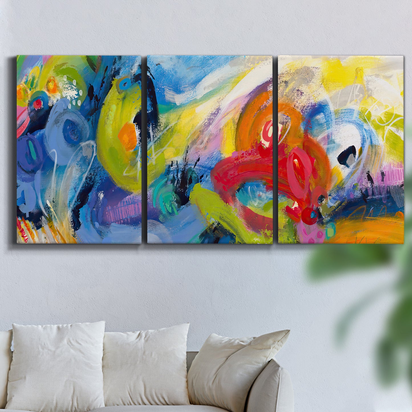 Three-panel canvas wall art featuring colorful abstract racing forms, displayed in a living room above a sofa.