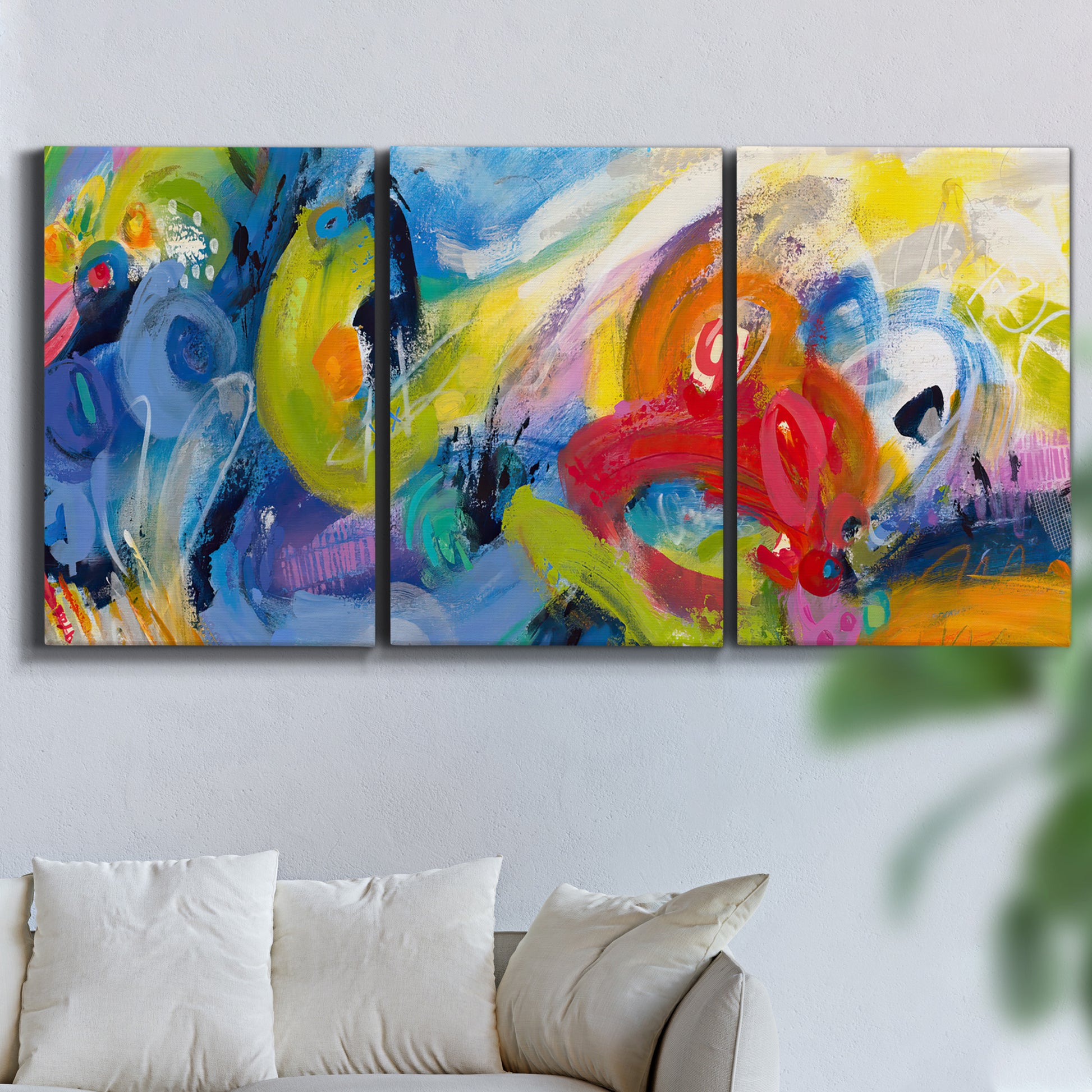 Three-panel canvas wall art featuring colorful abstract racing forms, displayed in a living room above a sofa.