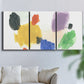 Three-panel canvas wall art featuring inkblot style abstract color symmetry, displayed in a living room above a sofa.