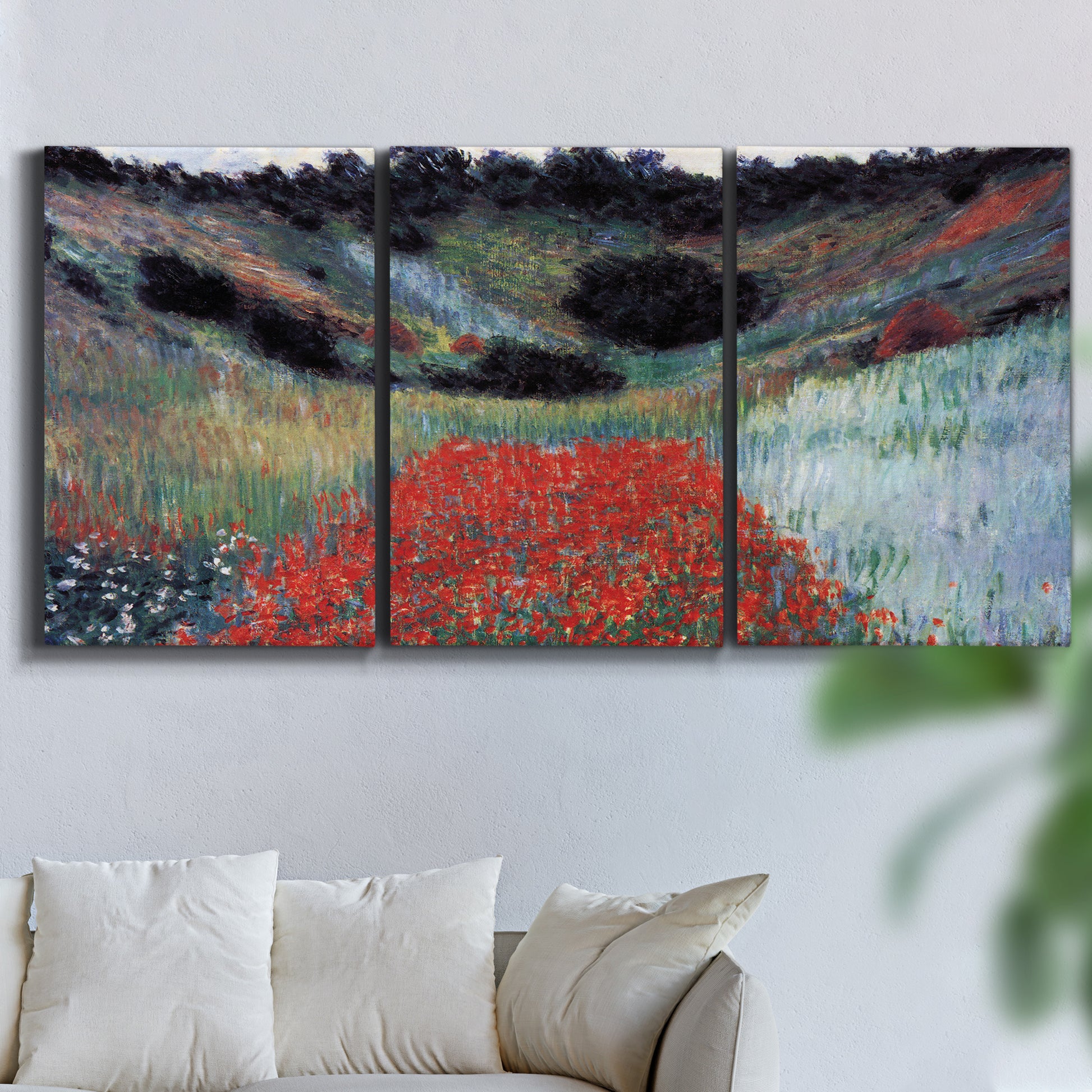 Three-panel canvas wall art featuring poppy field in shallow valley, displayed in a living room above a sofa.