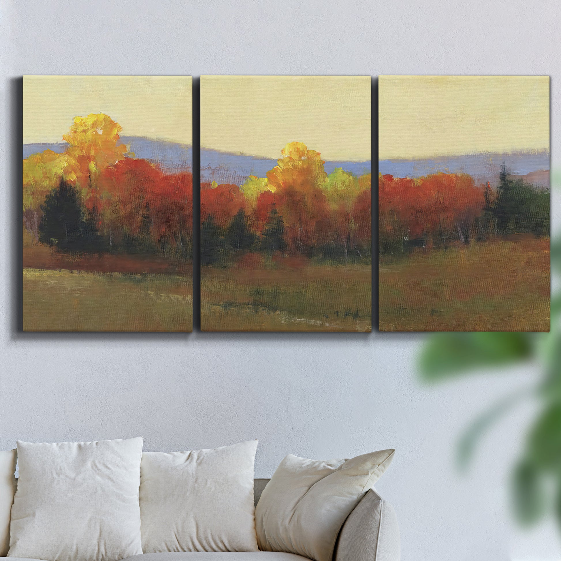 Three-panel canvas wall art featuring autumn landscape changing foliage, displayed in a living room above a sofa.