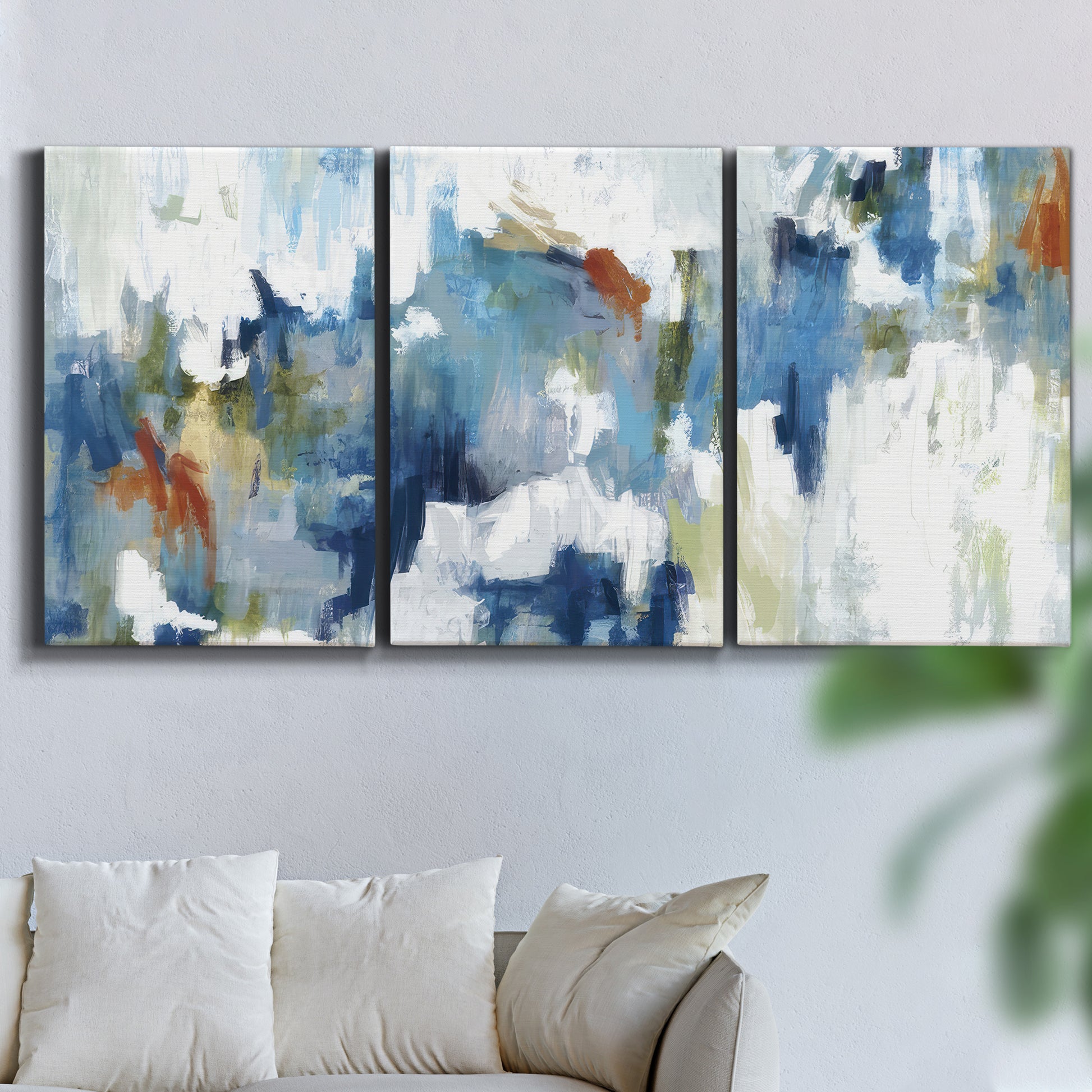 Three-panel canvas wall art featuring flowing abstract color movement, displayed in a living room above a sofa.