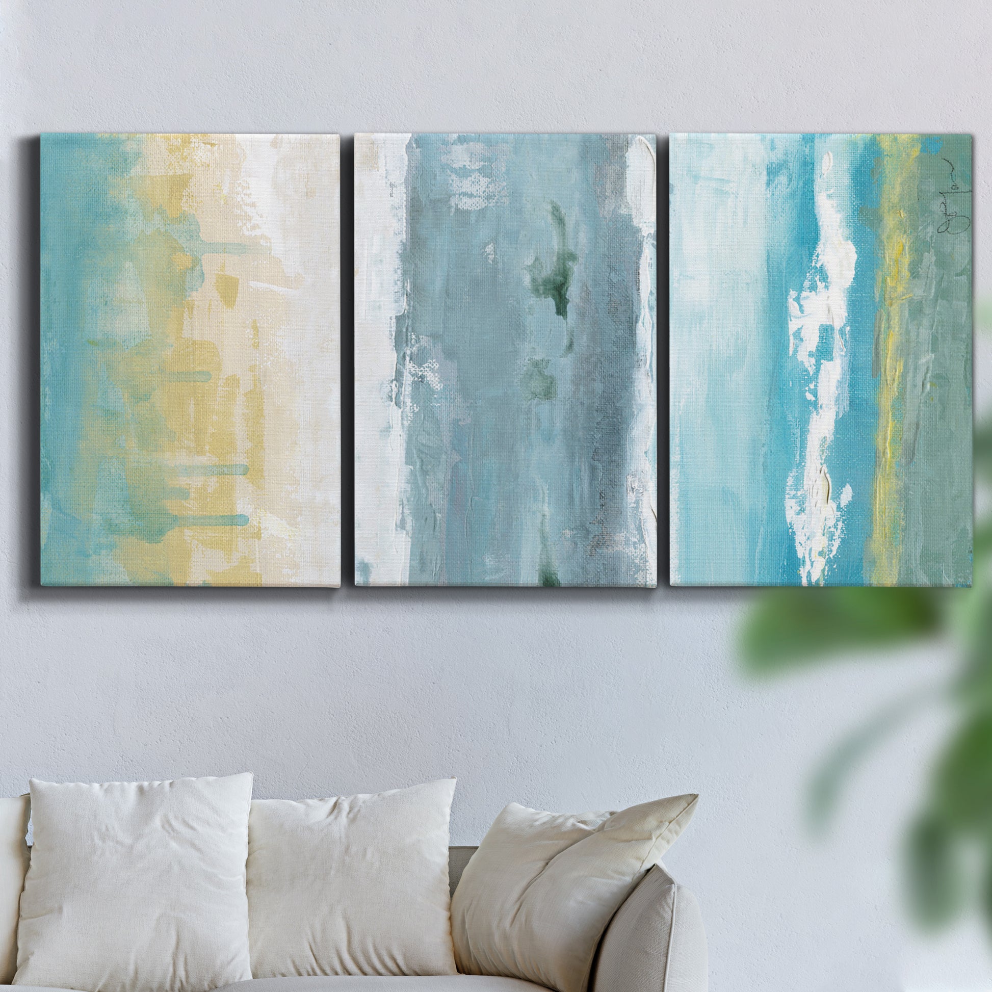 Three-panel canvas wall art featuring abstract coastal shoreline textures, displayed in a living room above a sofa.