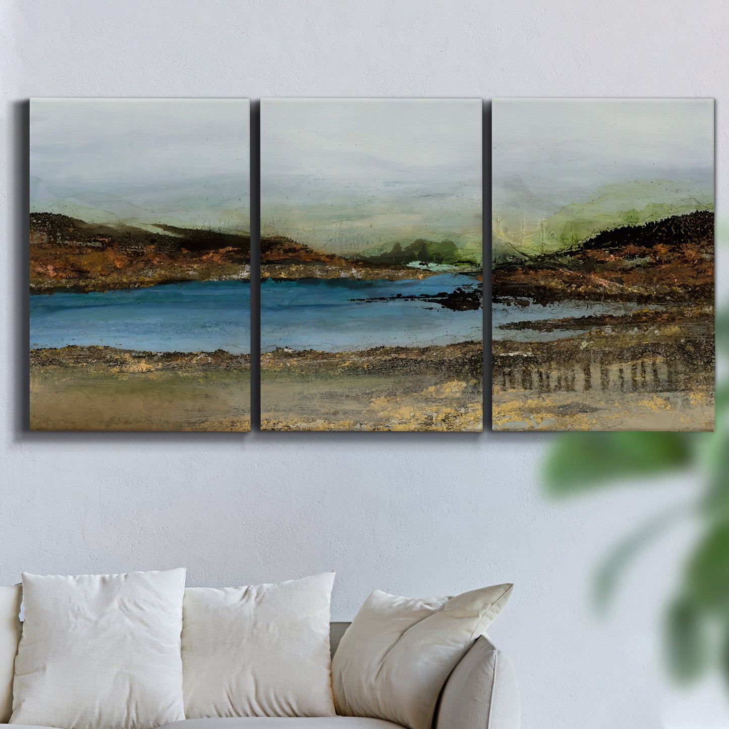 Three-panel canvas wall art featuring peaceful lakeside shoreline landscape, displayed in a living room above a sofa.