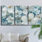 Three-panel canvas wall art featuring soft white floral abstraction, displayed in a living room above a sofa.