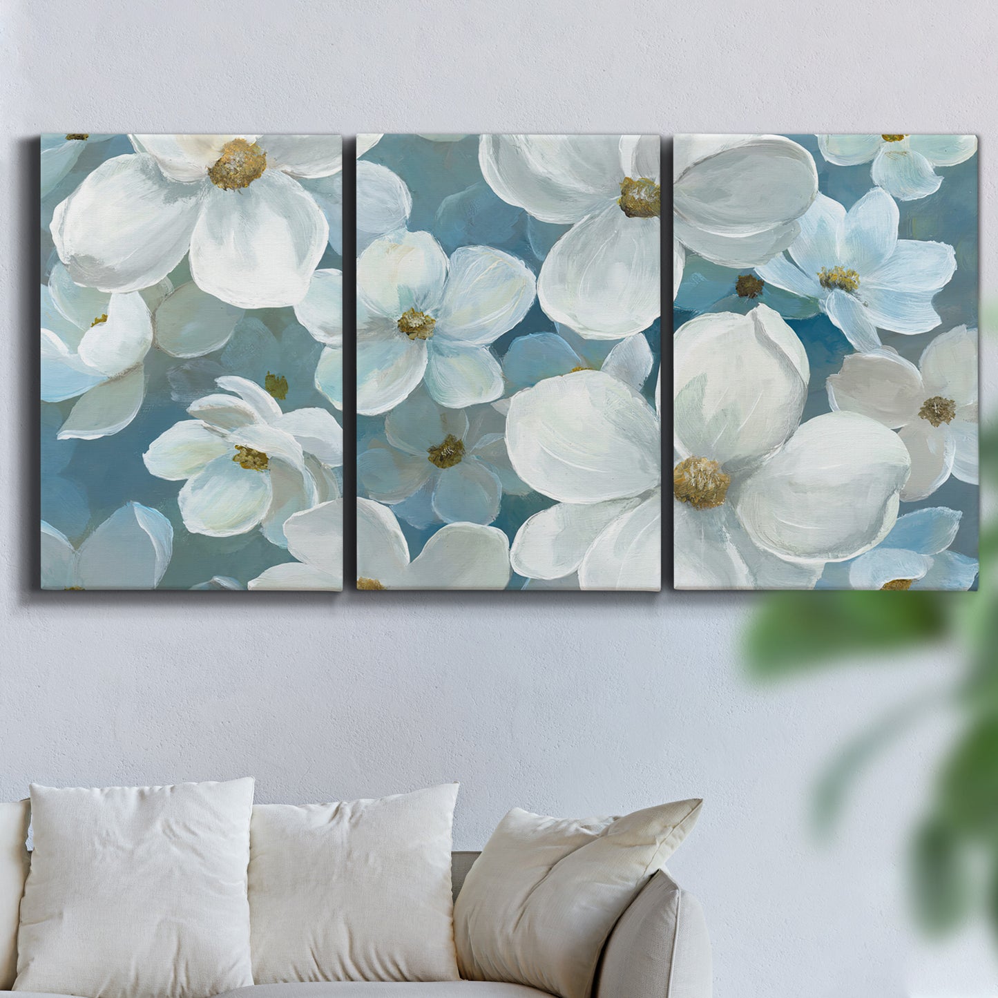 Three-panel canvas wall art featuring soft white floral abstraction, displayed in a living room above a sofa.