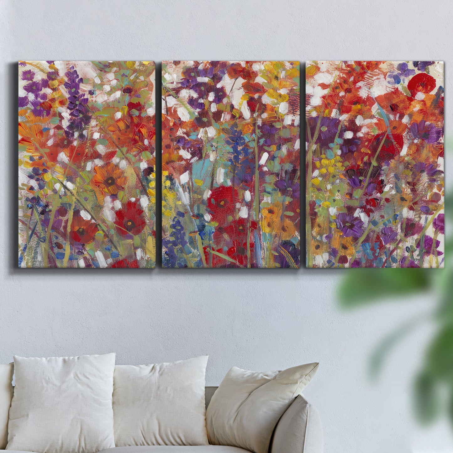 Three-panel canvas wall art featuring colorful floral arrangement, displayed in a living room above a sofa.
