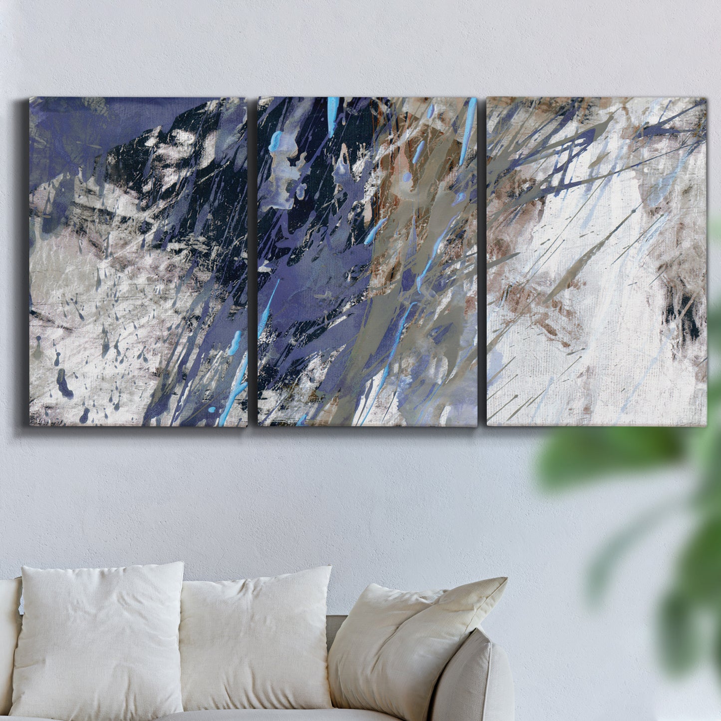 Three-panel canvas wall art featuring textured blue abstract composition, displayed in a living room above a sofa.