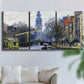 Three-panel canvas wall art featuring historic tower beside canal, displayed in a living room above a sofa.