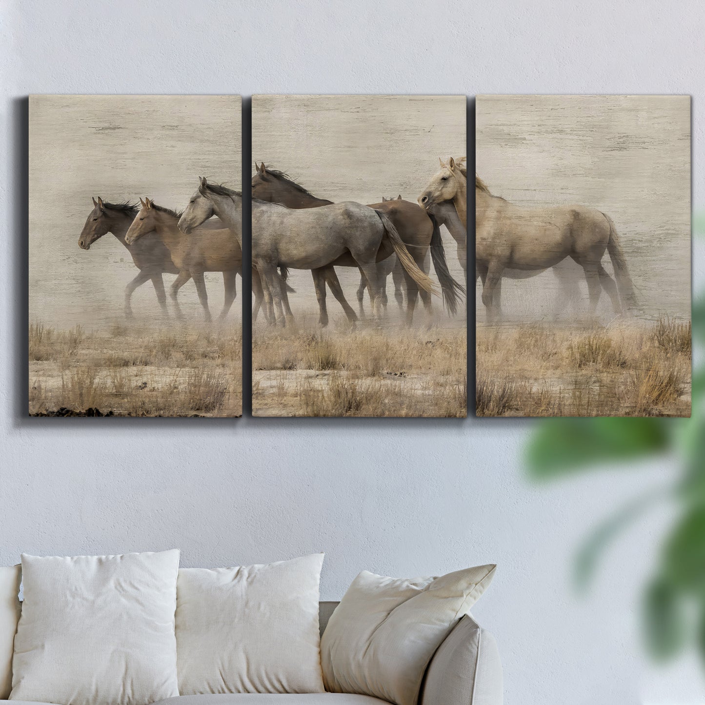 Three-panel canvas wall art featuring wild horses roaming open terrain, displayed in a living room above a sofa.