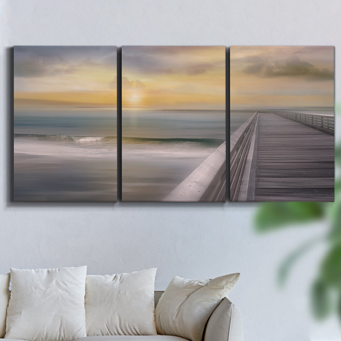 Three-panel canvas wall art featuring tropical beach at sunset photograph, displayed in a living room above a sofa.