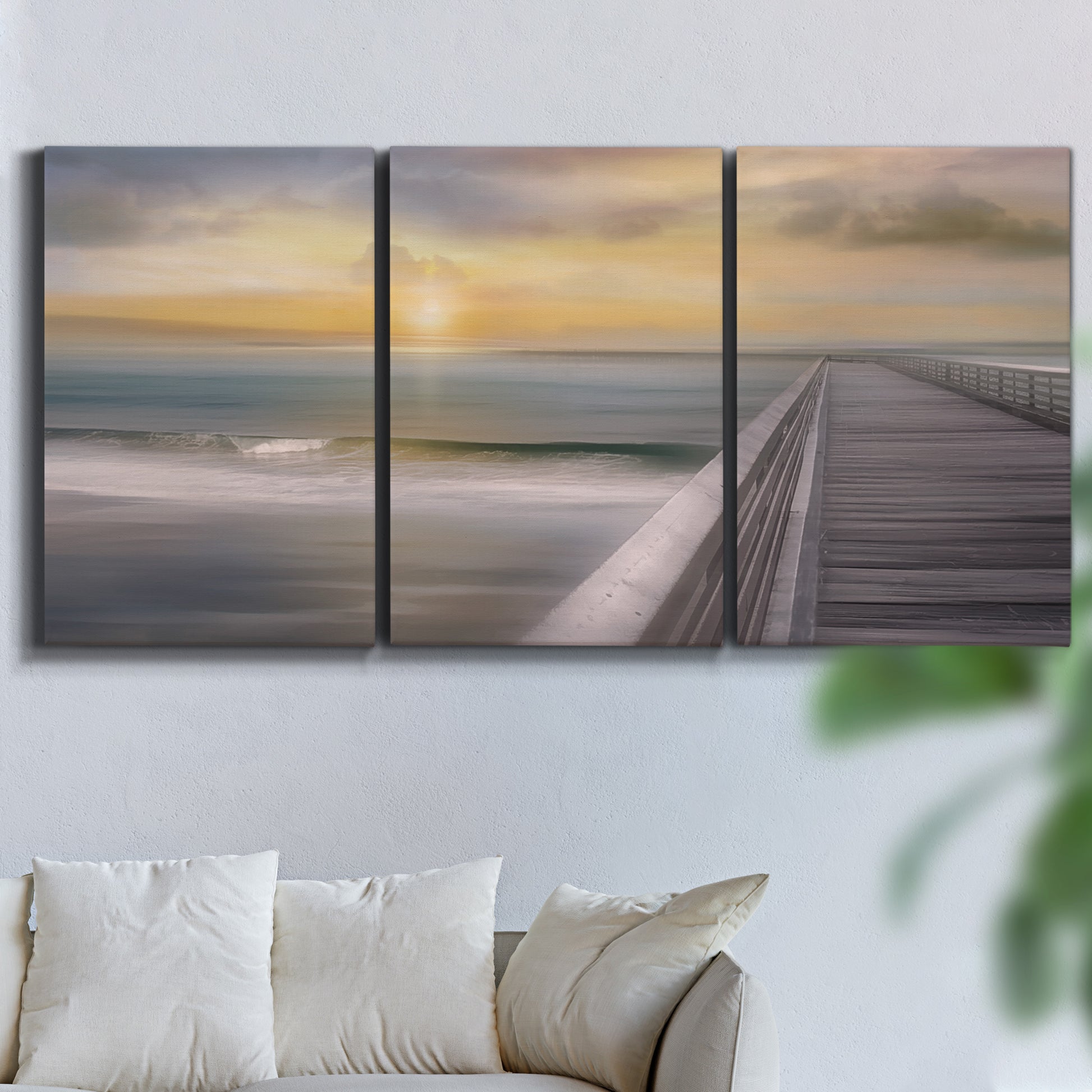Three-panel canvas wall art featuring tropical beach at sunset photograph, displayed in a living room above a sofa.
