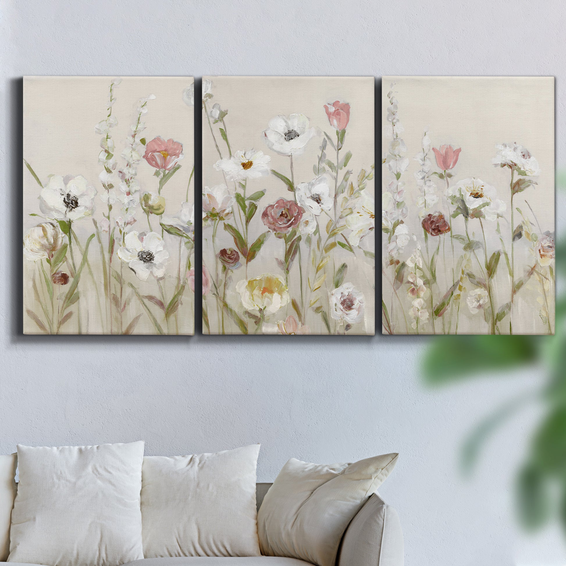 Three-panel canvas wall art featuring loose farmhouse style floral painting, displayed in a living room above a sofa.