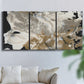 Three-panel canvas wall art featuring pale abstract mask like forms, displayed in a living room above a sofa.
