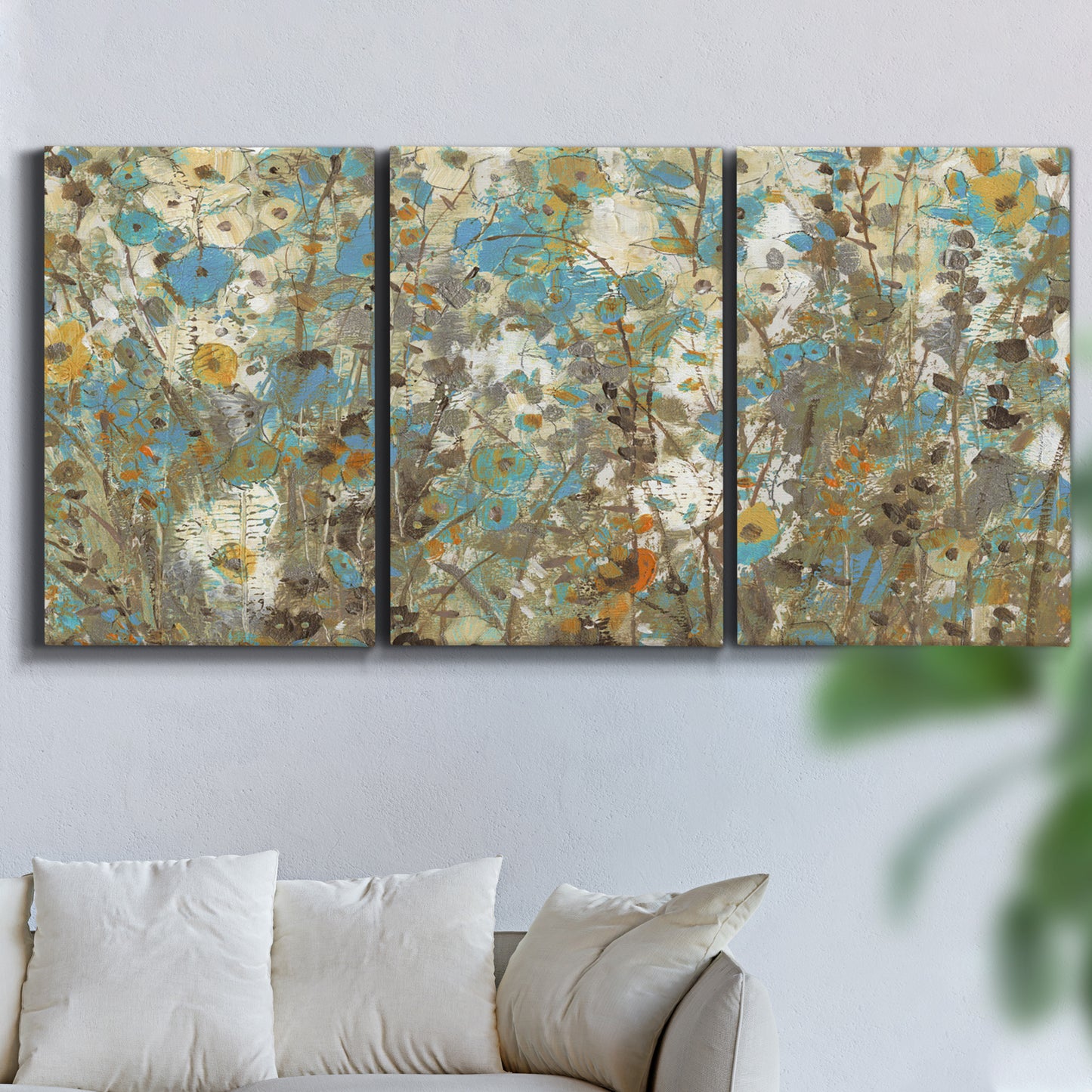 Three-panel canvas wall art featuring abstract flowering vine pattern, displayed in a living room above a sofa.