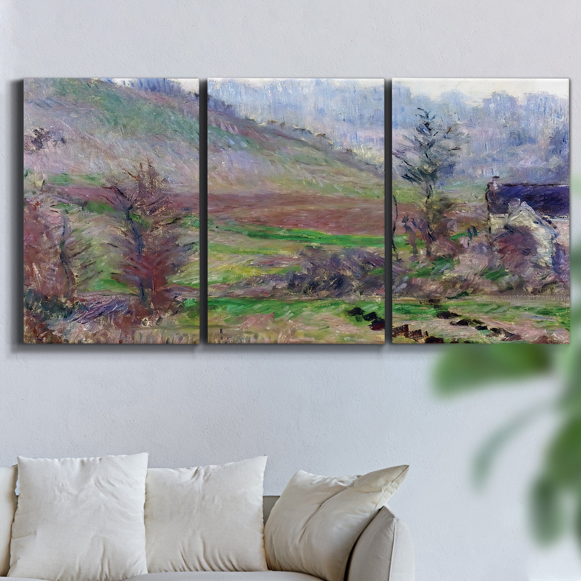 Three-panel canvas wall art featuring cliffside cottage overlooking sea, displayed in a living room above a sofa.