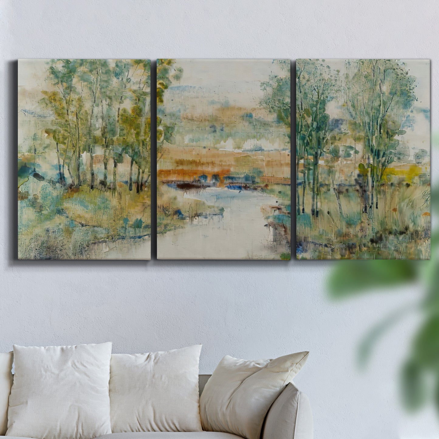 Three-panel canvas wall art featuring trees lining quiet creek, displayed in a living room above a sofa.