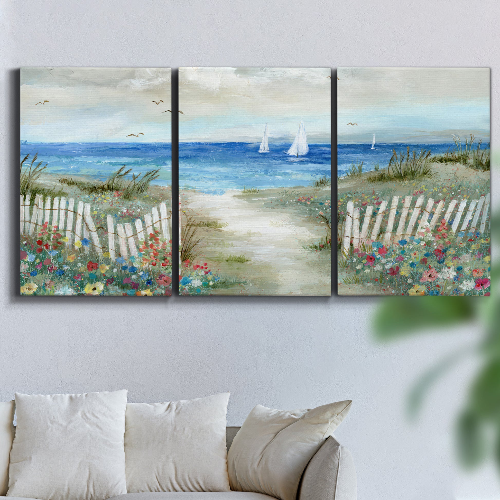 Three-panel canvas wall art featuring lush coastal garden landscape, displayed in a living room above a sofa.
