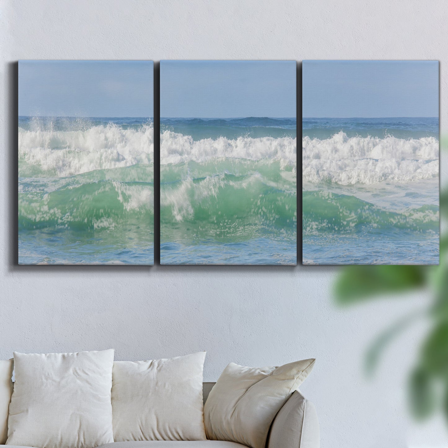 Three-panel canvas wall art featuring coastal waves breaking ashore, displayed in a living room above a sofa.