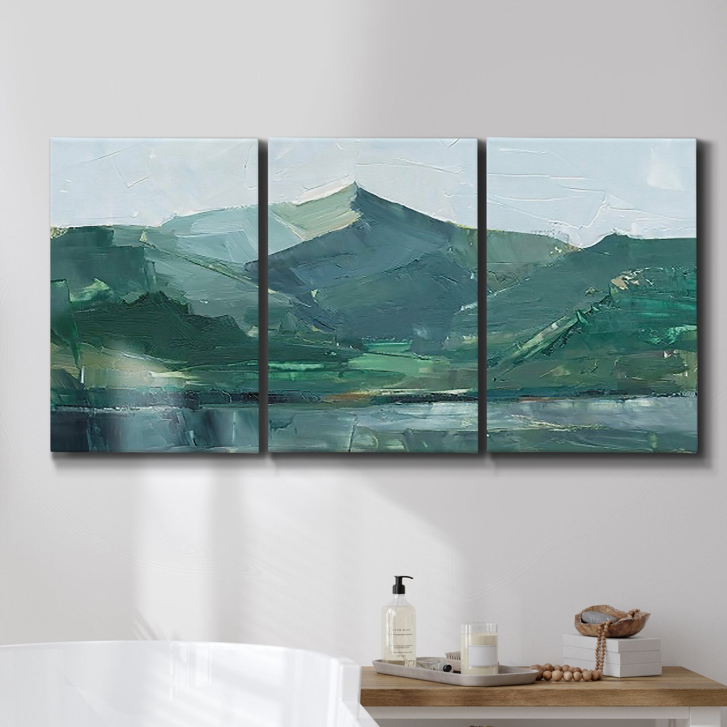 Three-panel canvas wall art featuring muted mountain range in grey tones, displayed in a bathroom above a bathtub.