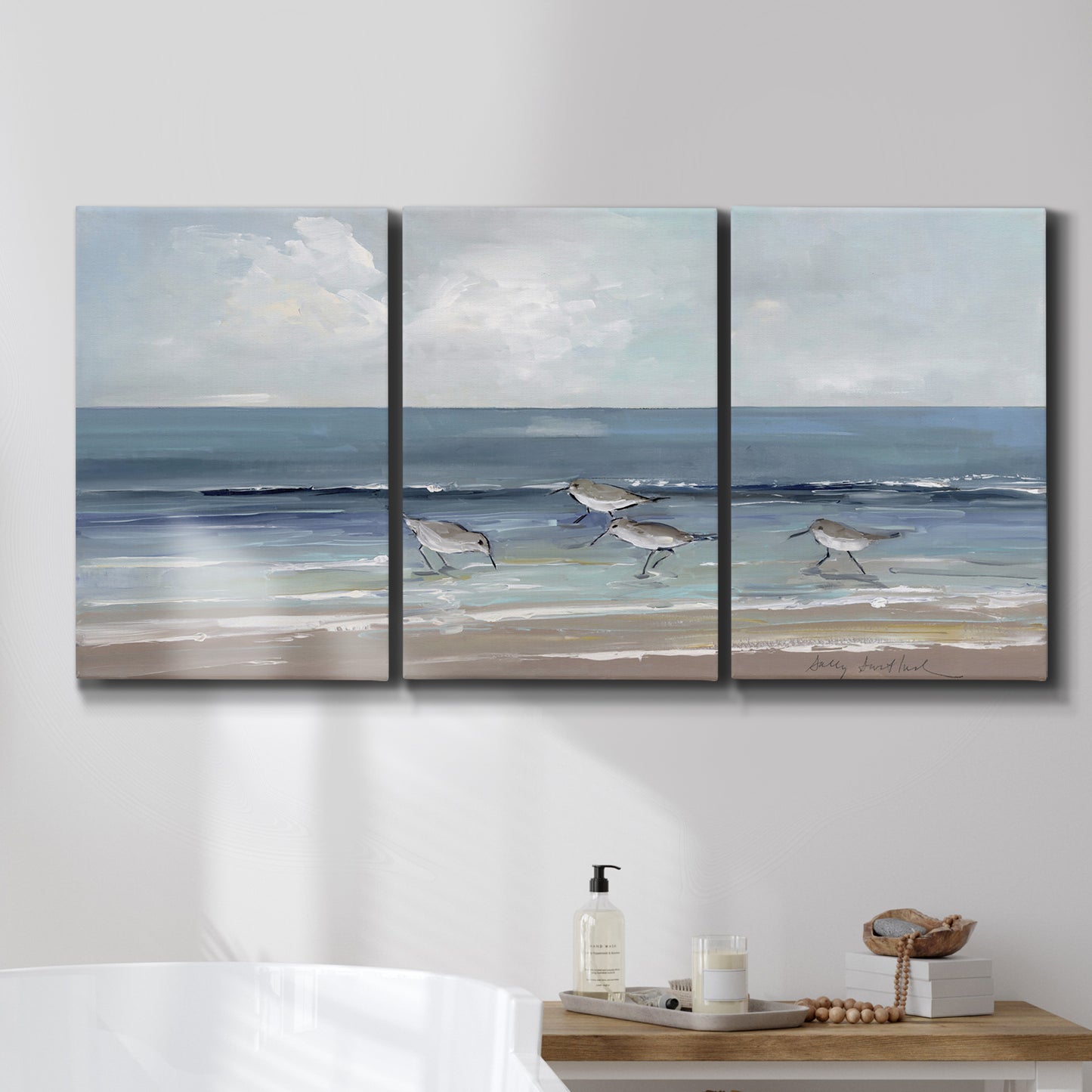 Three-panel canvas wall art featuring shore birds searching along beach, displayed in a bathroom above a bathtub.