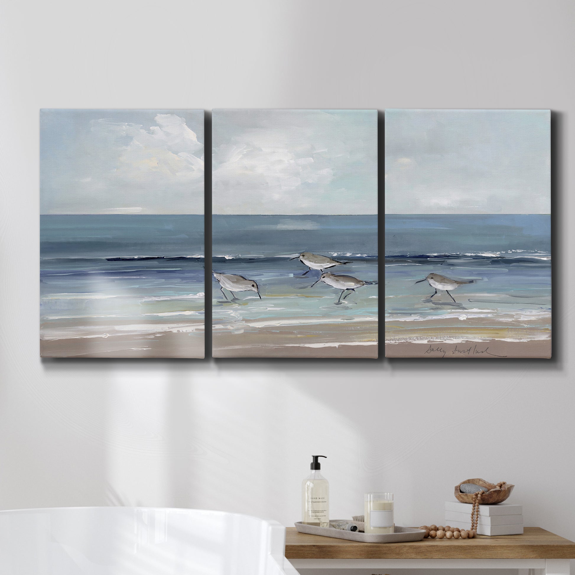 Three-panel canvas wall art featuring shore birds searching along beach, displayed in a bathroom above a bathtub.